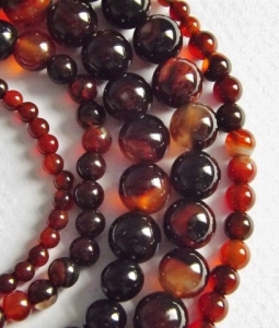 image of some strands of highly polished round agate beads in a variety of sizes