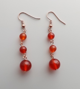 image shows a pair of rose gold earrings made from 3 round red agate beads on links, dropping down