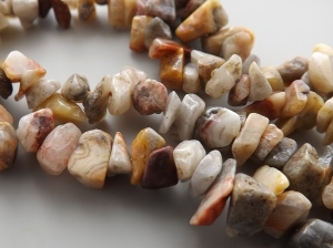 photo shows a close up of some crazy lace agate nugget beads, with vibrant patterns and swirls in brown, cream, red and yellow hues