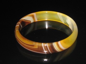 Image shows a yellow beige and brown banded agate carved and highly polished bangle, carved from one piece of agate