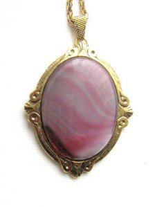 photo shows a close up of a large banded agate cabochon, which has been dyed a pale magenta pink colour
