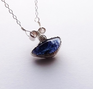 image shows a handmade horizontal oval blue john fluorite pendant,bezel set and with two curling little loops at the top as a bail